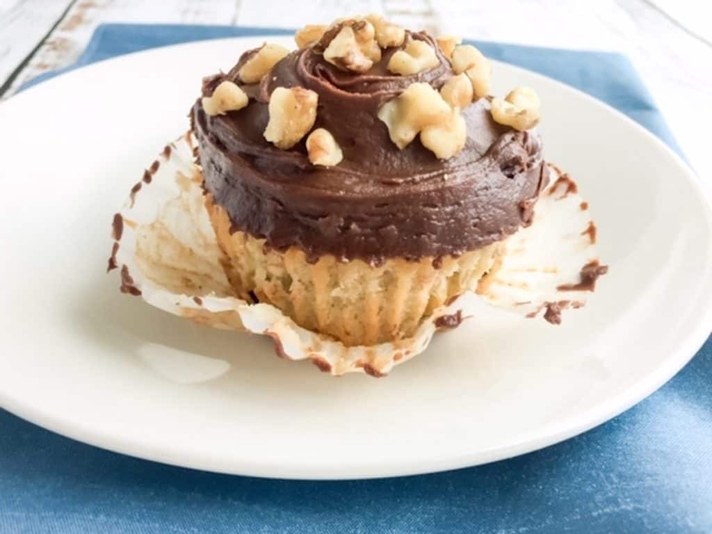 Chocolate and banana cupcake in wrapper on white plate