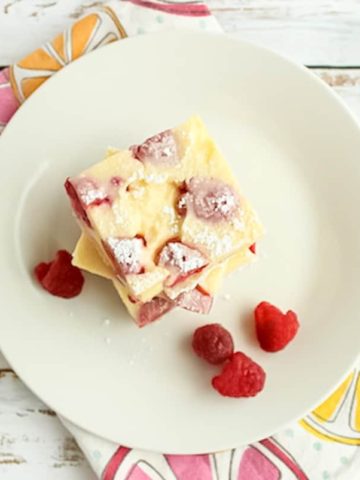 Lemon bars on a white plate with raspberries