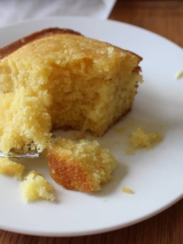 Single square of sweetened cornbread on white plate with fork