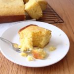 Slice of cornbread on white plate with a bite sitting on a fork
