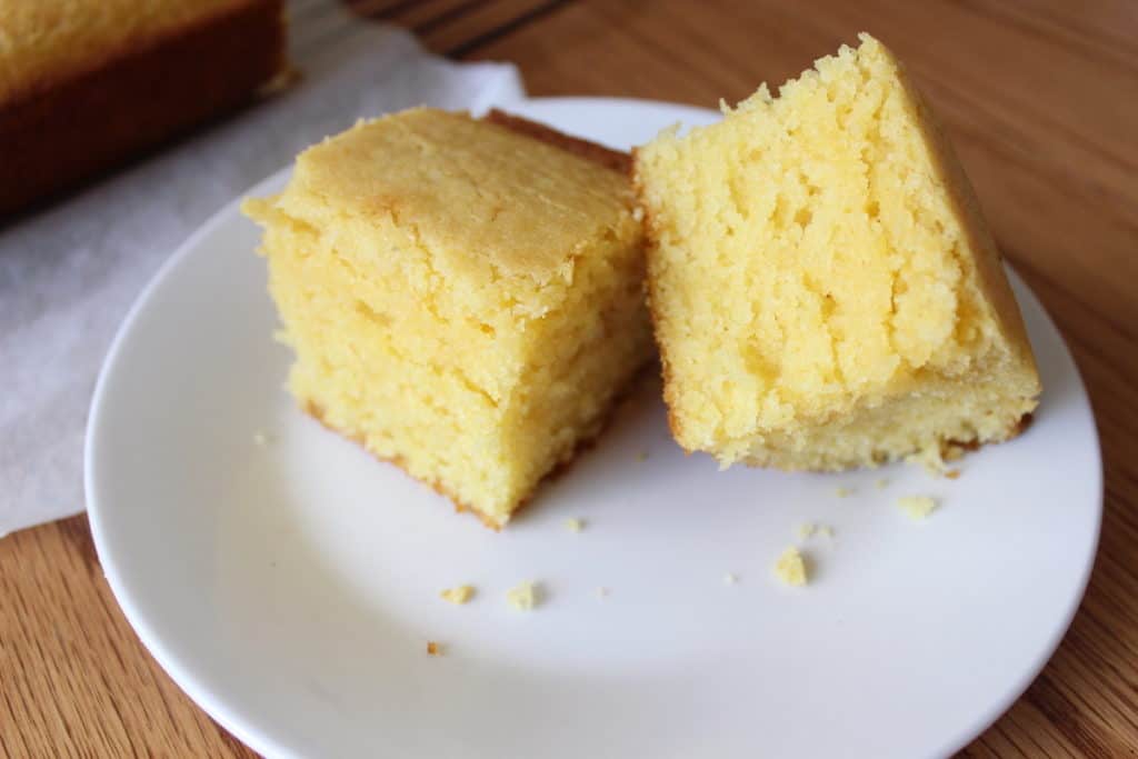 Two pieces of cornbread on a white plate