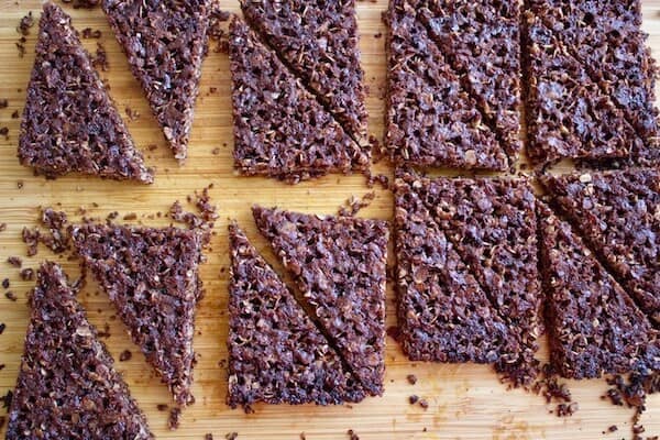 baked chocolate oat slice cut into wedges on a wooden cutting board