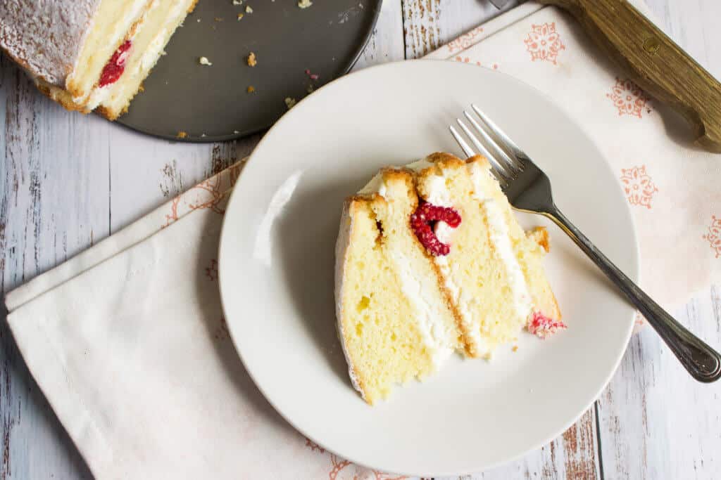 single slice or raspberry cake on a white plate with a fork