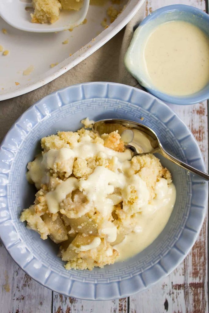 apple crumble with custard in blue bowl