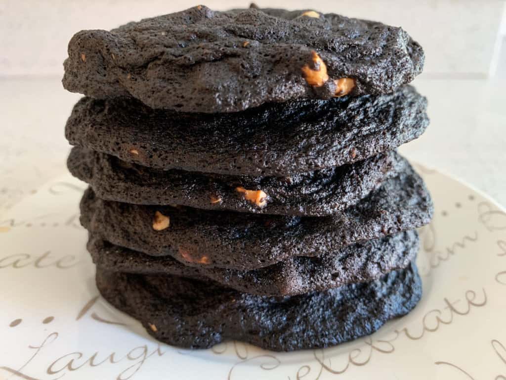 stack of thin chocolate cashew cookies on white plate