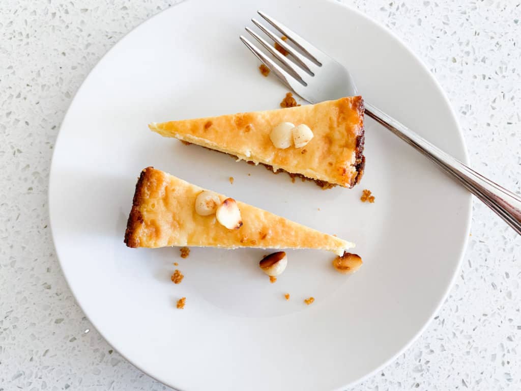 Two slices of white chocolate macadamia tart on white plate with fork