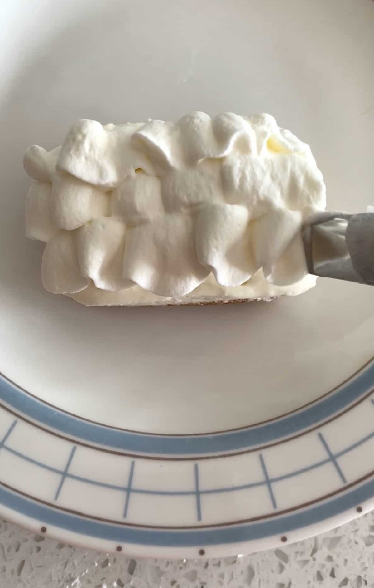 piping whipped cream onto cheesecake