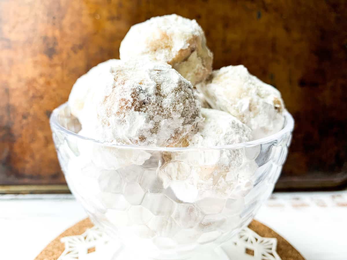 A pile of Italian butterball cookies in a clear bowl.