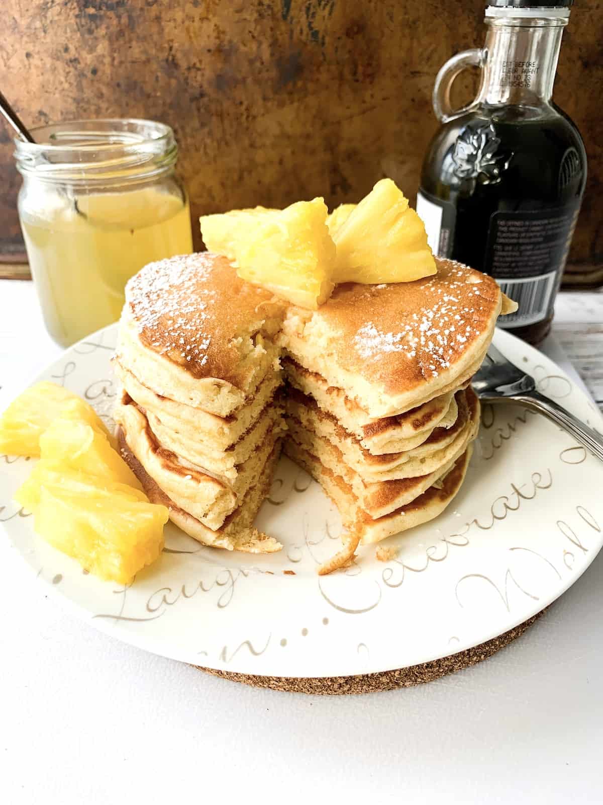 Pancake stack on a white plate drizzled with pineapple syrup.