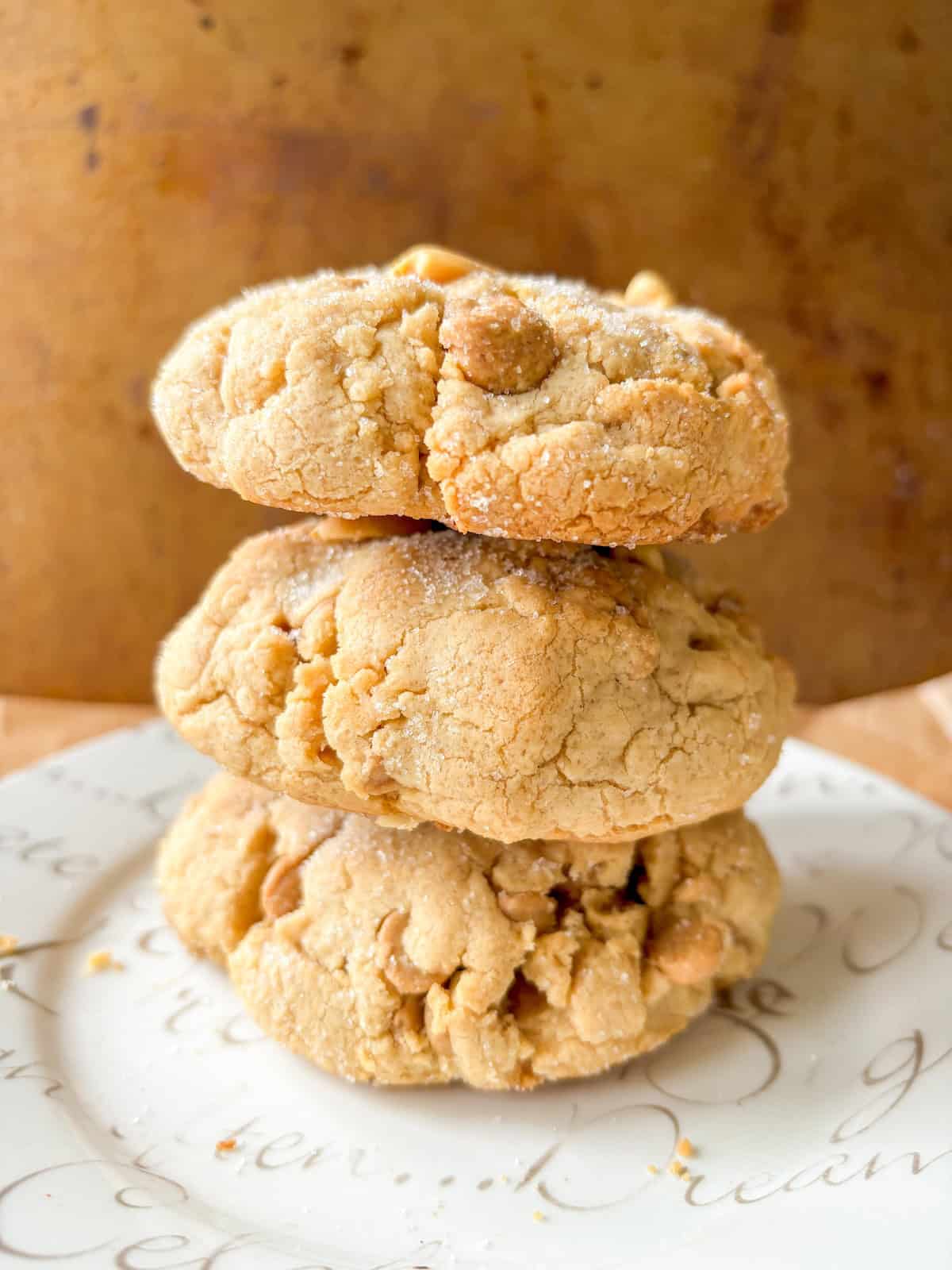 3 brown butter peanut butter cookies stacked on a white plate.