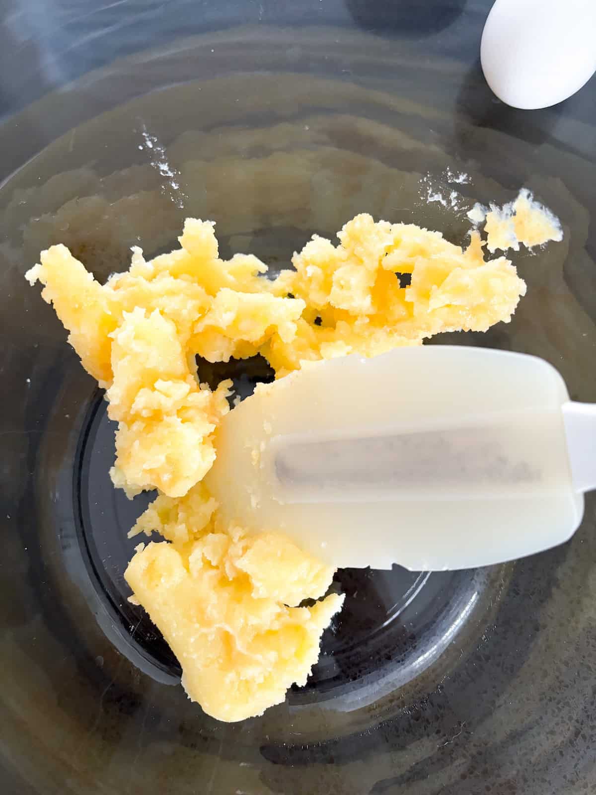 cooled browned butter in a glass mixing bowl with a white spatula

