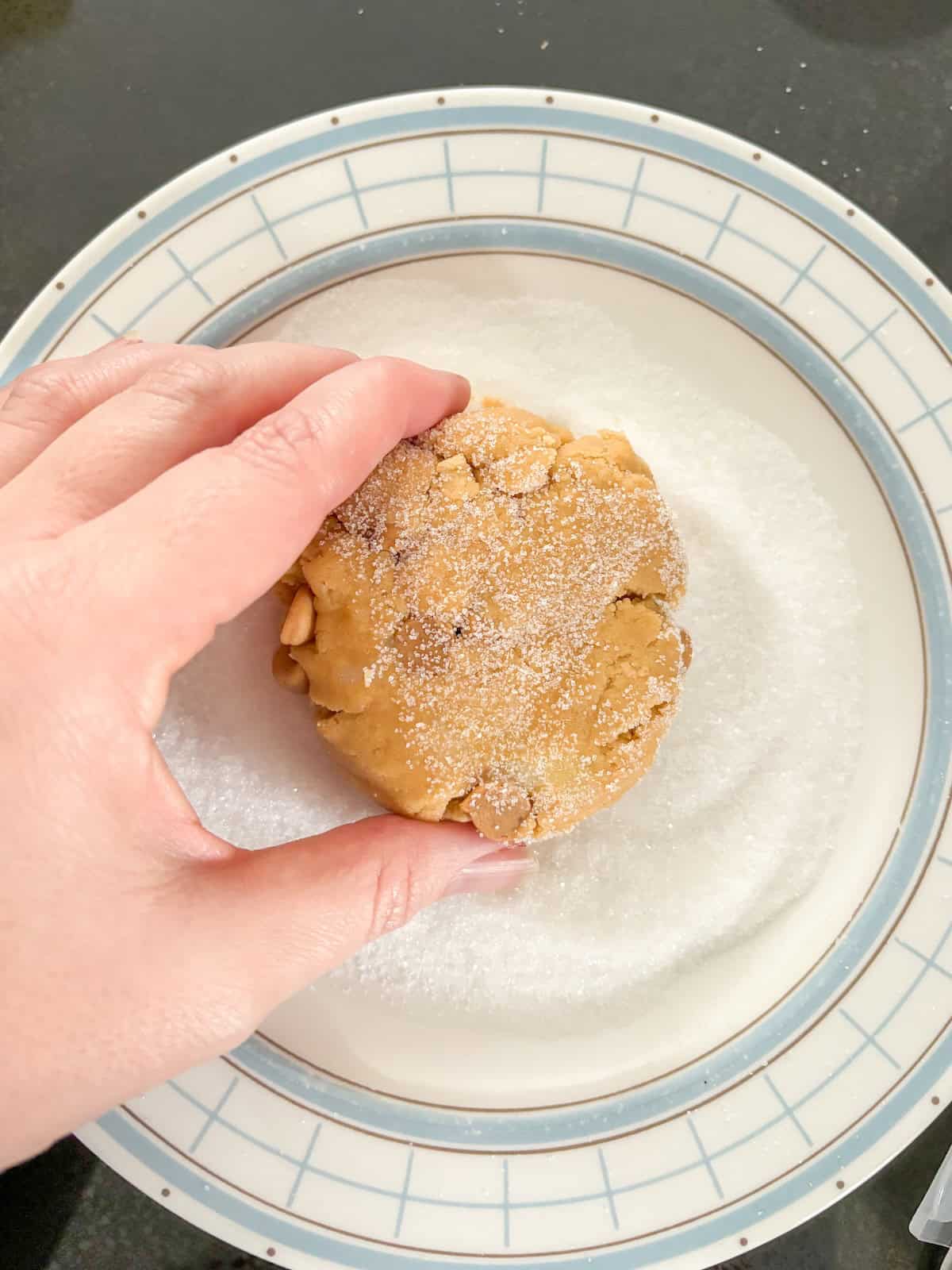 dipping peanut butter cookie dough ball in white sugar