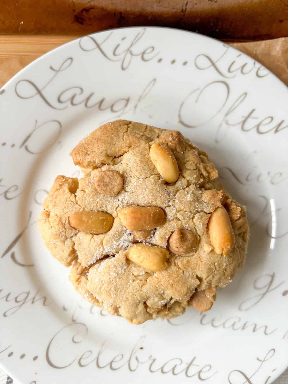 single brown butter peanut butter cookie on a white plate with decorative writing
