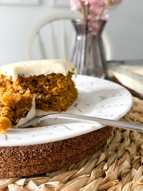 slice of cake on white plate. A bite is sitting on a fork ready to eat.