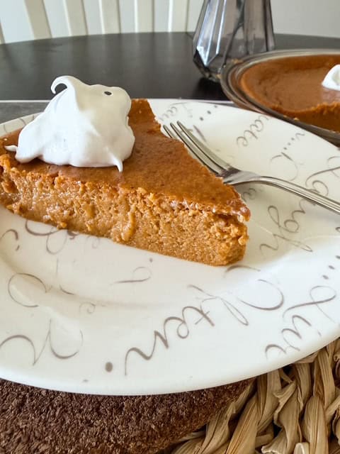 This image shows a slice of pumpkin impossible pie on white plate looking from the side.